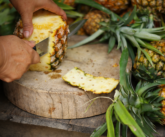 Ananas die geschild wordt op een houten plank